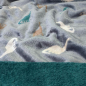 Preview: Kuscheliger Wellnessfleece in dusty blue mit Dinosaurier gemustert