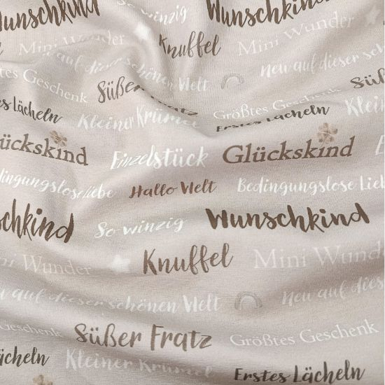 Weicher Baumwolljersey in hellem Nougat mit Babywords gemustert