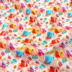 Leicht fallender Baumwollstoff in Peach Farbtönen mit bunten Mini Elefanten gemustert